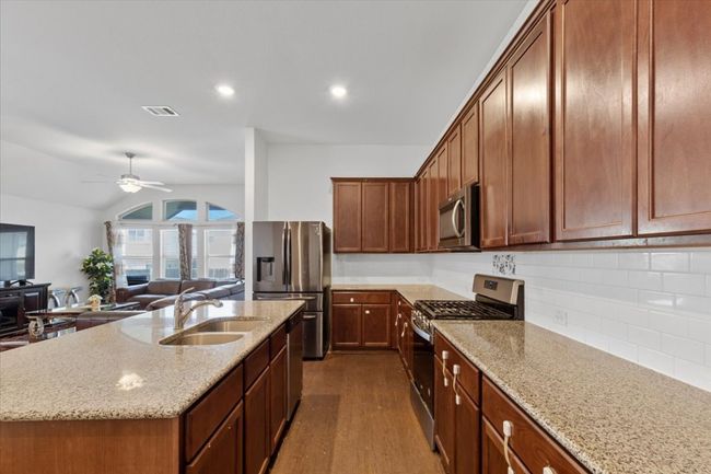 Kitchen with a sink, dark wood finished floors, visible vents, a ceiling fan, and appliances with stainless steel finishes | Image 11