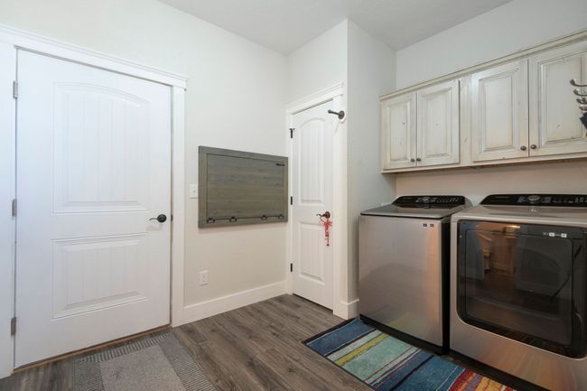 Washroom with cabinet space, washing machine and dryer, and dark wood finished floors | Image 17