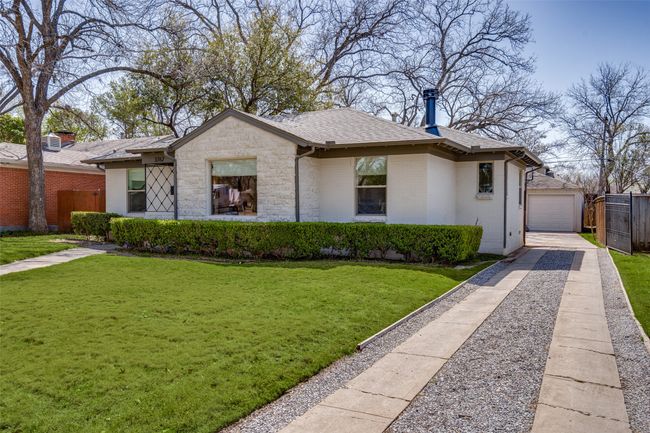 Bungalow with driveway, an outbuilding, a shingled roof, brick siding, and a detached garage | Image 24
