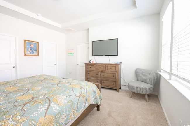 Bedroom with a tray ceiling, baseboards, and light carpet | Image 12