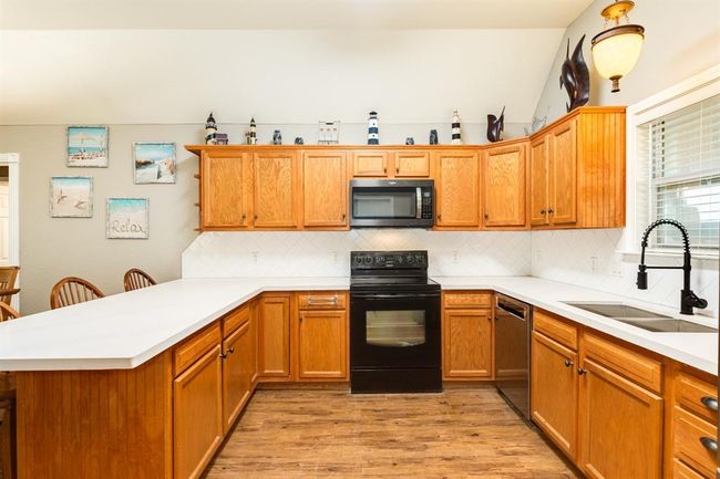 Bright kitchen featuring wooden cabinetry, and recently installed quartz white with gray countertop. The room is accented with decorative items and wall art, creating a welcoming atmosphere. | Image 10