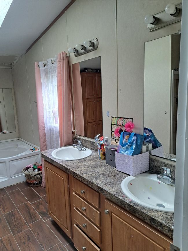 Bathroom featuring double vanity, a tub, lofted ceiling, and tile patterned flooring | Image 9