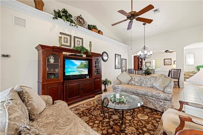 Living area featuring visible vents, ceiling fan with notable chandelier, light tile patterned floors, and high vaulted ceiling | Image 14