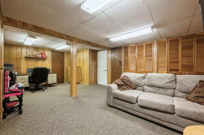 Carpeted living room featuring a drop ceiling and wood walls | Image 21