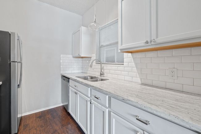 Kitchen featuring a sink, stainless steel appliances, light stone countertops, and white cabinets | Image 8