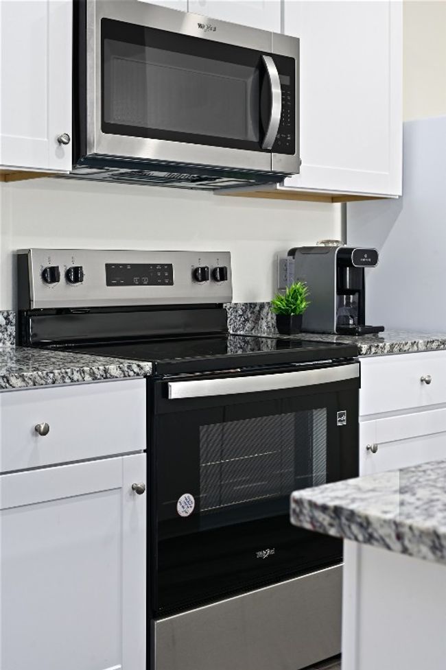 Kitchen with stainless steel appliances, white cabinetry, and light stone counters | Image 22