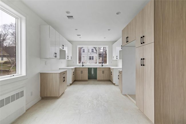 Kitchen featuring radiator heating unit, visible vents, dishwashing machine, and a sink | Image 16