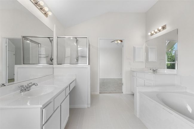 Bathroom with vaulted ceiling, two vanities, a garden tub, a stall shower, and tile patterned flooring | Image 17
