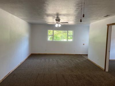 Carpeted empty room with ceiling fan and a textured ceiling | Image 2