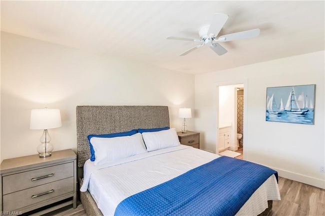 Bedroom featuring wood finished floors, baseboards, ceiling fan, and ensuite bathroom | Image 13