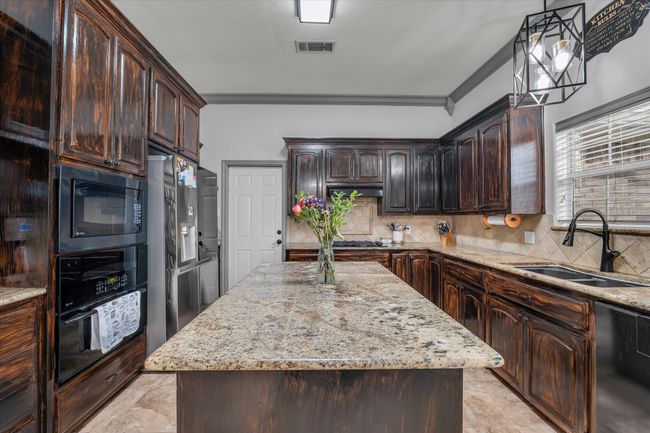 Kitchen featuring a sink, black appliances, dark brown cabinets, decorative backsplash, and ornamental molding | Image 8