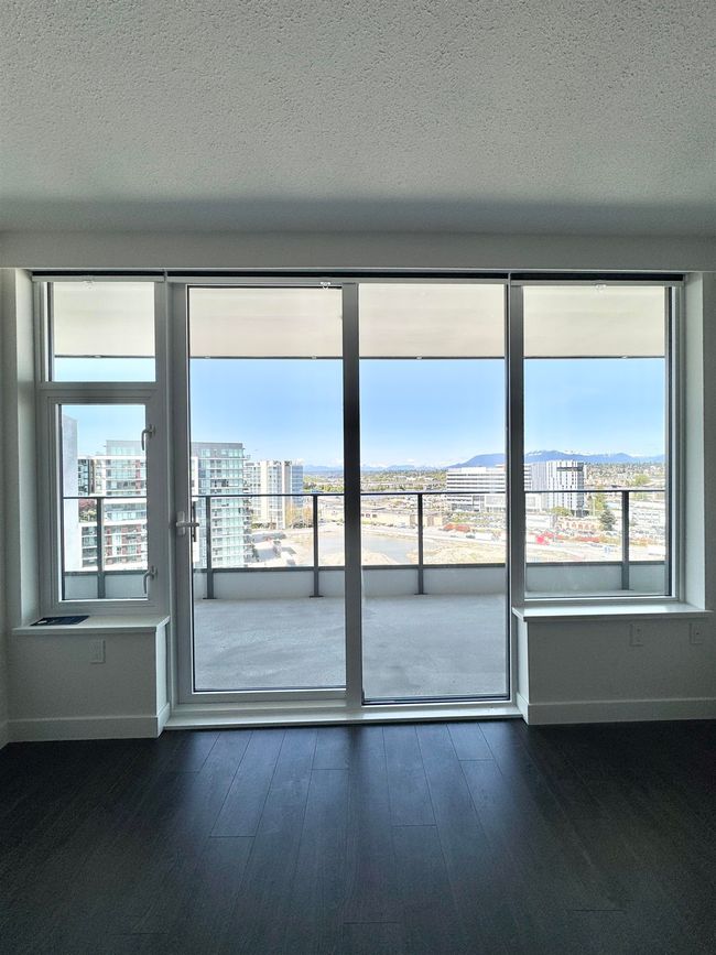 Interior space with a city view, a textured ceiling, baseboards, and dark wood-style floors | Image 6
