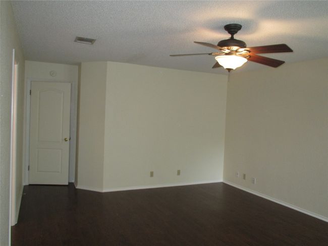 Empty room featuring dark wood-style flooring, ceiling fan, and a textured ceiling | Image 11