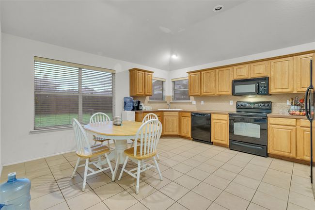 Kitchen featuring black appliances, lofted ceiling, tasteful backsplash, light countertops, and light tile patterned floors | Image 8