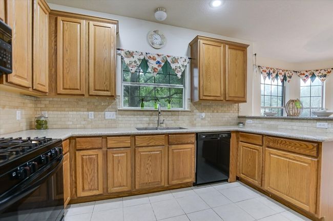 Kitchen featuring black appliances, a sink, healthy amount of natural light, and brown cabinets | Image 8