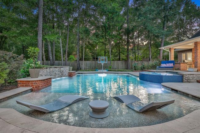 The pool, installed in 2021, features a pebble finish for a sleek, modern look, along with a sun shelf perfect for in-water lounging. Beautiful rock wall accents with cascading waterfalls enhance the tranquil, resort-style ambiance, making this backyard a private oasis designed for both relaxation and recreation. | Image 45