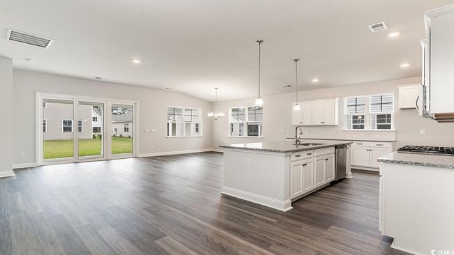 Kitchen with white cabinetry, dark wood-type flooring, a kitchen island with sink, light stone countertops, and sink | Image 9