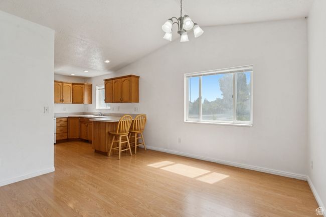Kitchen featuring a chandelier, light wood-style flooring, a breakfast bar, light countertops, and a peninsula | Image 5