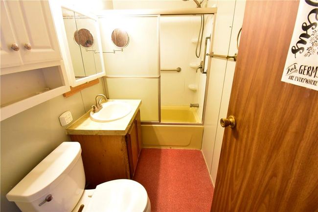 Full bathroom featuring bath / shower combo with glass door, vanity, and toilet | Image 28