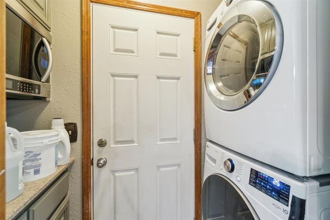 Washroom featuring stacked washing machine and dryer and a textured wall | Image 33
