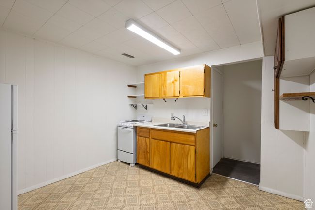 Kitchen featuring white appliances, open shelves, light countertops, brown cabinetry, and light floors | Image 30