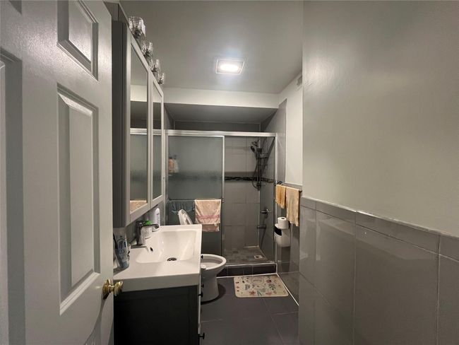 Full bathroom featuring tile walls, vanity, tile patterned floors, a stall shower, and wainscoting | Image 13