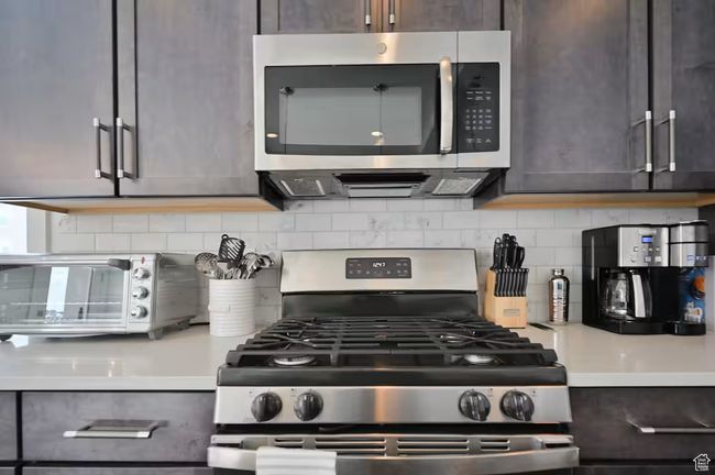 Kitchen with appliances with stainless steel finishes, light countertops, tasteful backsplash, and dark brown cabinetry | Image 10