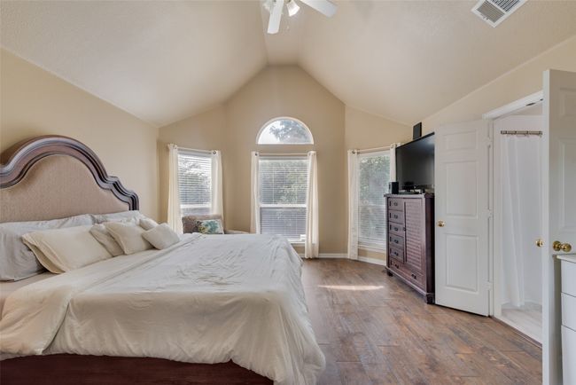Upstairs primary bedroom featuring multiple windows, wood finished floors, and lofted ceiling | Image 16