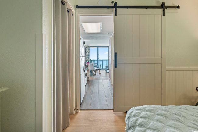 Bedroom featuring wood finished floors, a barn door, a textured wall, and freestanding refrigerator | Image 6