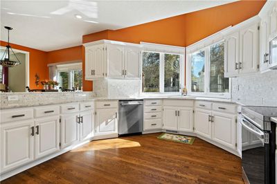 Kitchen featuring white cabinets, appliances with stainless steel finishes, and dark hardwood floors | Image 1