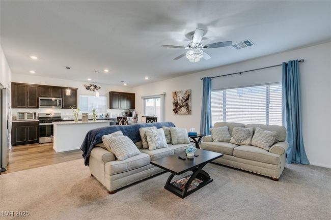 Living area with a wealth of natural light, visible vents, recessed lighting, and a ceiling fan | Image 11