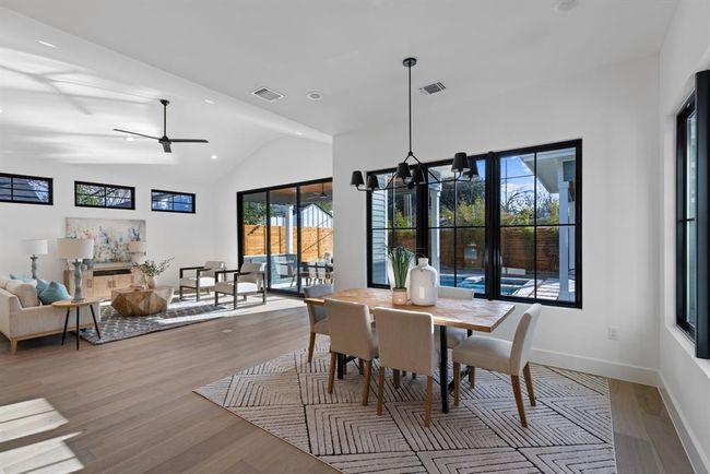 Dining room with wood finished floors, vaulted ceiling, a chandelier, baseboards, and recessed lighting | Image 20