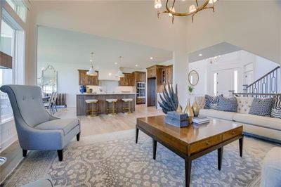 Living room featuring an inviting chandelier, sink, a high ceiling, and light wood-type flooring | Image 1