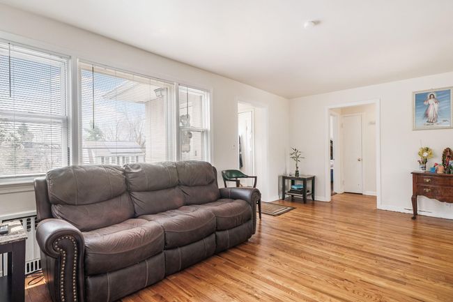 Living area with radiator, light wood-style floors, and baseboards | Image 8