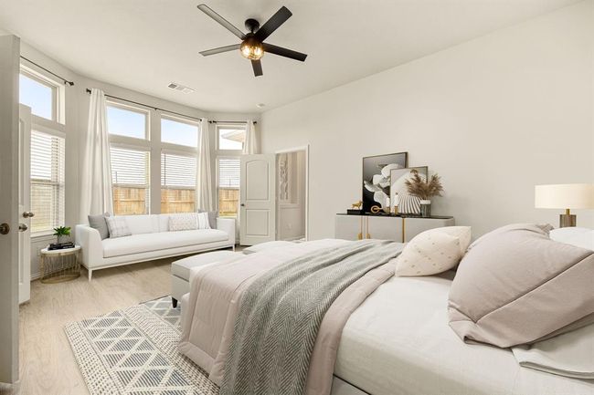 What a wonderful place to come home to, this stunning primary suite greets you with gorgeous wood floors, a warm custom paint, high ceiling, ceiling fan with lighting, lovely arched windows allowing in natural light brightening up this spacious primary bedroom, with extra space for a seating area. *Virtually Staged | Image 12