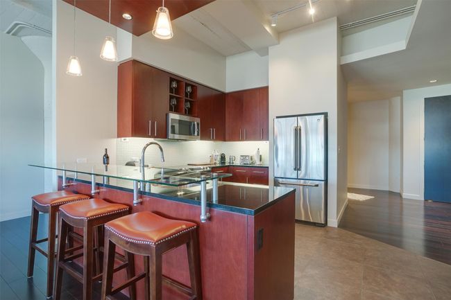 Kitchen featuring appliances with stainless steel finishes, a peninsula, decorative light fixtures, tasteful backsplash, and rail lighting | Image 15