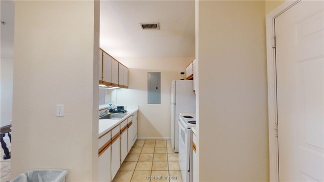 Kitchen featuring electric panel, white range with electric cooktop, white cabinets, sink, and light tile patterned flooring | Image 8