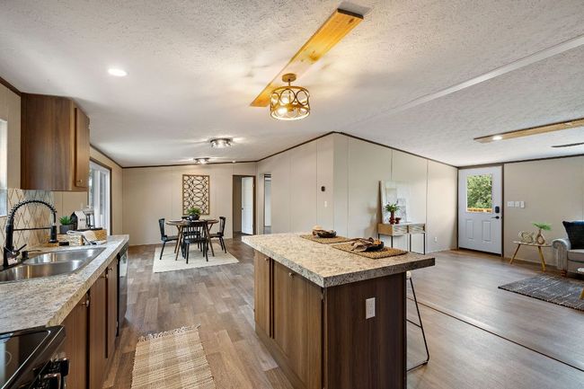 Kitchen featuring light wood finished floors, black range with electric stovetop, a sink, and a textured ceiling | Image 18