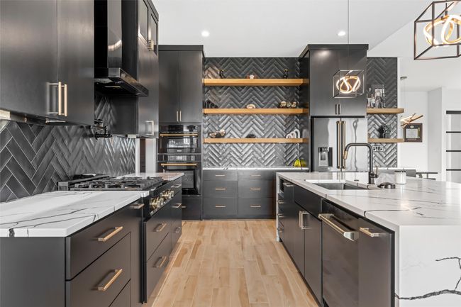 Kitchen with stainless steel appliances, open shelves, dark cabinetry, pendant lighting, and a sink | Image 12