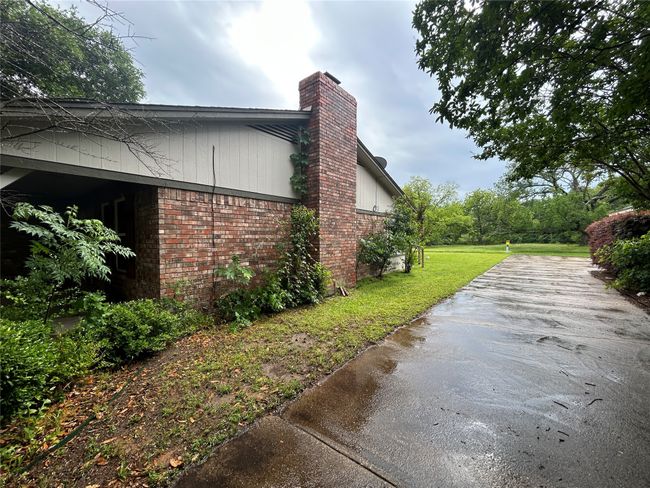 View of property exterior featuring a chimney, brick siding, and a lawn | Image 4