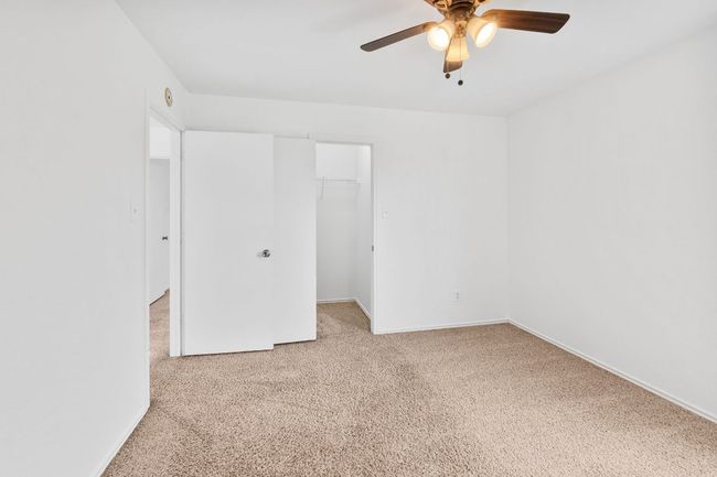 Unfurnished bedroom with light carpet, a spacious closet, baseboards, a closet, and ceiling fan | Image 26