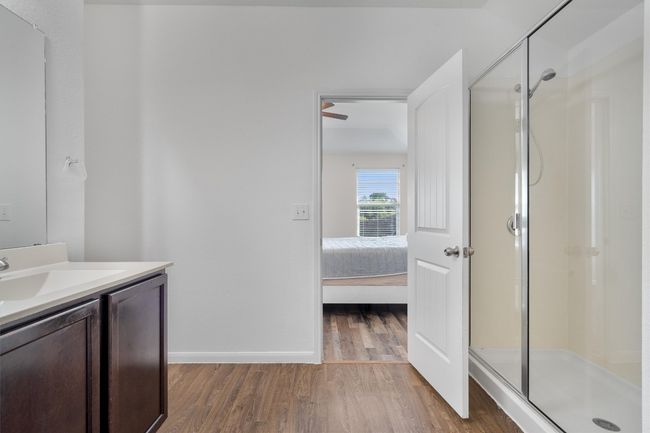 Full bathroom featuring wood finished floors, a shower stall, vanity, baseboards, and ensuite bath | Image 17