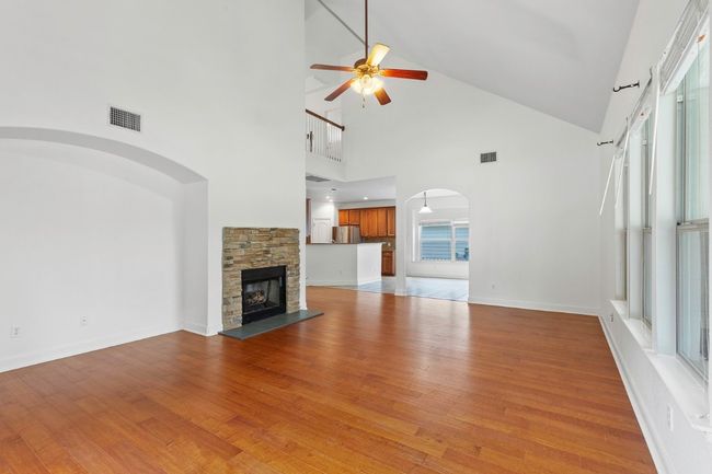Spacious living room with ceiling fan, arched walkways, high vaulted ceiling, plenty of natural light, and wood floors | Image 12