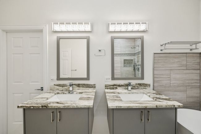Primary bathroom featuring two vanities, tiled shower, and stand alone bathtub | Image 20