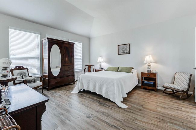 Step into the luxurious primary suite—a true sanctuary crafted for relaxation and comfort. A wall of windows bathes the space in natural light, while rich wood-look tile flooring adds warmth and serenity. | Image 14