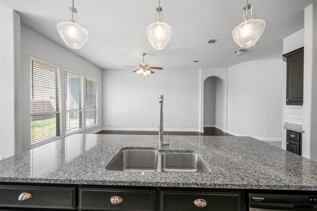 Kitchen featuring visible vents, a ceiling fan, a sink, open floor plan, and stone counters | Image 20