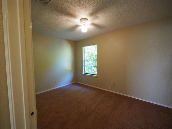 Spare room with dark carpet, baseboards, a textured ceiling, and ceiling fan | Image 16