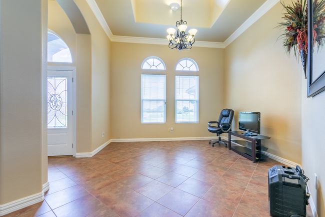 Unfurnished room featuring a chandelier, arched walkways, a raised ceiling, tile patterned flooring, and crown molding | Image 5
