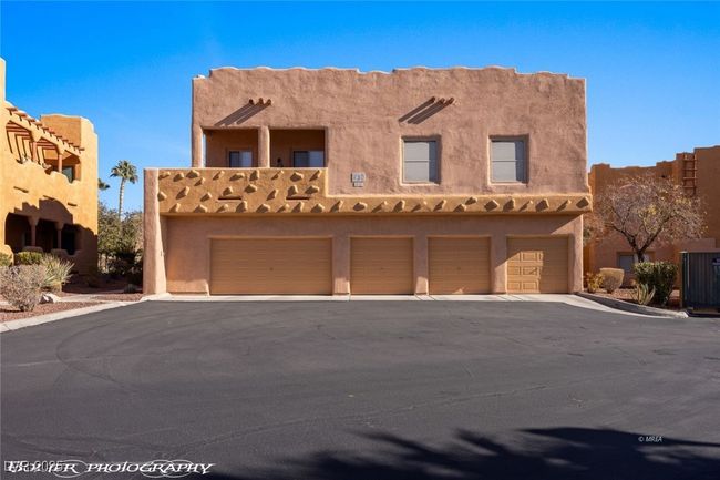 Pueblo revival-style home featuring driveway, stucco siding, and a garage | Image 51