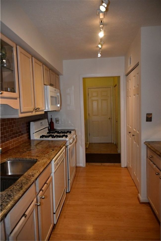Through the galley kitchen to the laundry along the left, and garage door to the right | Image 20